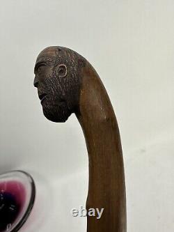 Art populaire ancien sculpté en bois représentant le visage d'un homme des montagnes vagabond mendiant avec une canne de marche.