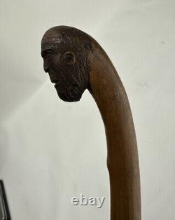 Art populaire ancien sculpté en bois représentant le visage d'un homme des montagnes vagabond mendiant avec une canne de marche.