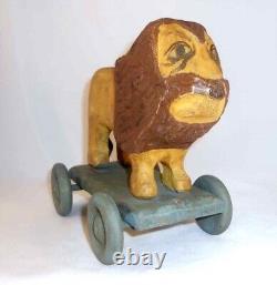 Jouet de traction en bois sculpté et peint à la main de style folklorique primitif représentant un lion contemporain sur roues.