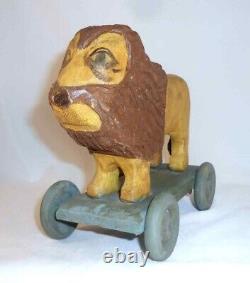 Jouet de traction en bois sculpté et peint à la main de style folklorique primitif représentant un lion contemporain sur roues.