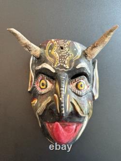 Masque de diable en bois sculpté rouge et noir, art populaire mexicain avec des yeux jaunes et une énorme langue