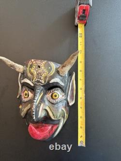 Masque de diable en bois sculpté rouge et noir, art populaire mexicain avec des yeux jaunes et une énorme langue