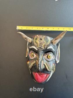 Masque de diable en bois sculpté rouge et noir, art populaire mexicain avec des yeux jaunes et une énorme langue