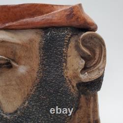 Masque en bois sculpté d'art populaire rustique, homme barbu, yeux creux, décoration des arrière-pays.