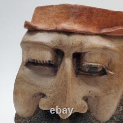 Masque en bois sculpté d'art populaire rustique, homme barbu, yeux creux, décoration des arrière-pays.