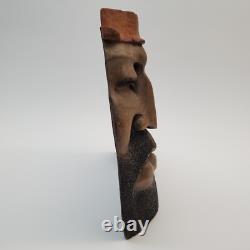 Masque en bois sculpté d'art populaire rustique, homme barbu, yeux creux, décoration des arrière-pays.