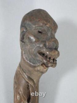 Poignée de canne de marche primitive en bois sculpté d'art populaire antique avec visage grotesque et crâne.